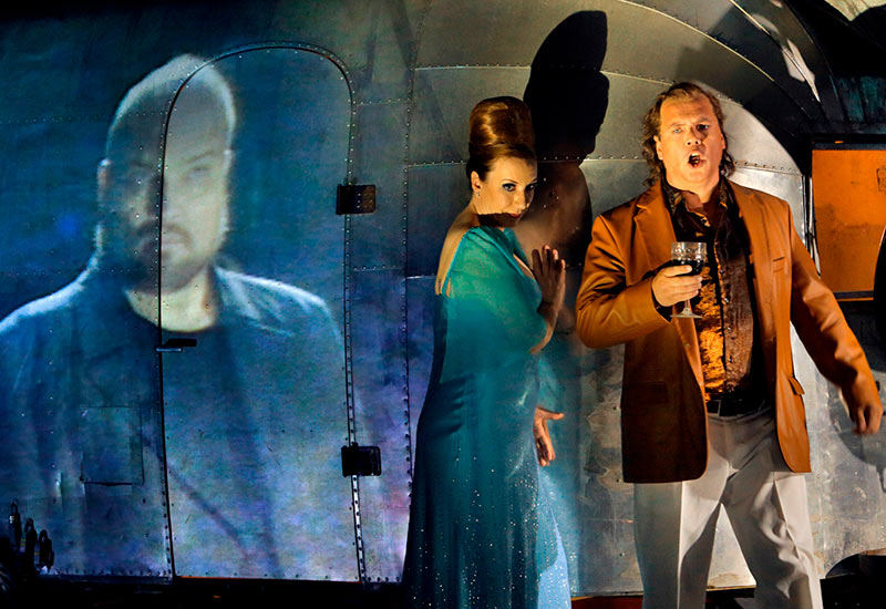 Stefan Vinke (Siegfried) and Alison Oakes (Gutrune). To the left, on video, Hagen (Stephen Milling) is watching. Photo: Enrico Nawrath / Bayreuther Festspiele